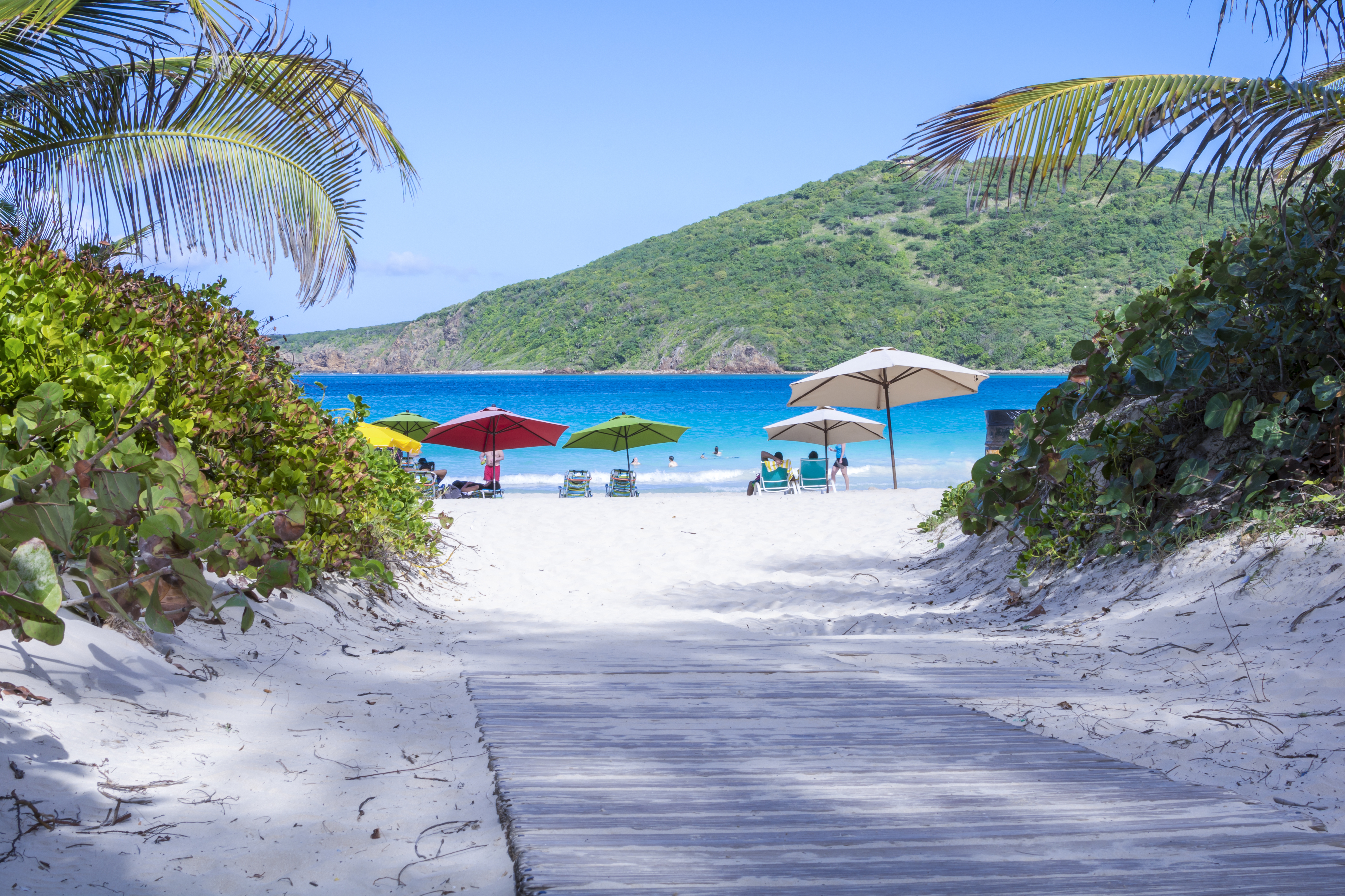 White sands of Flamenco Beach with colourful umbrellas and the ocean in background