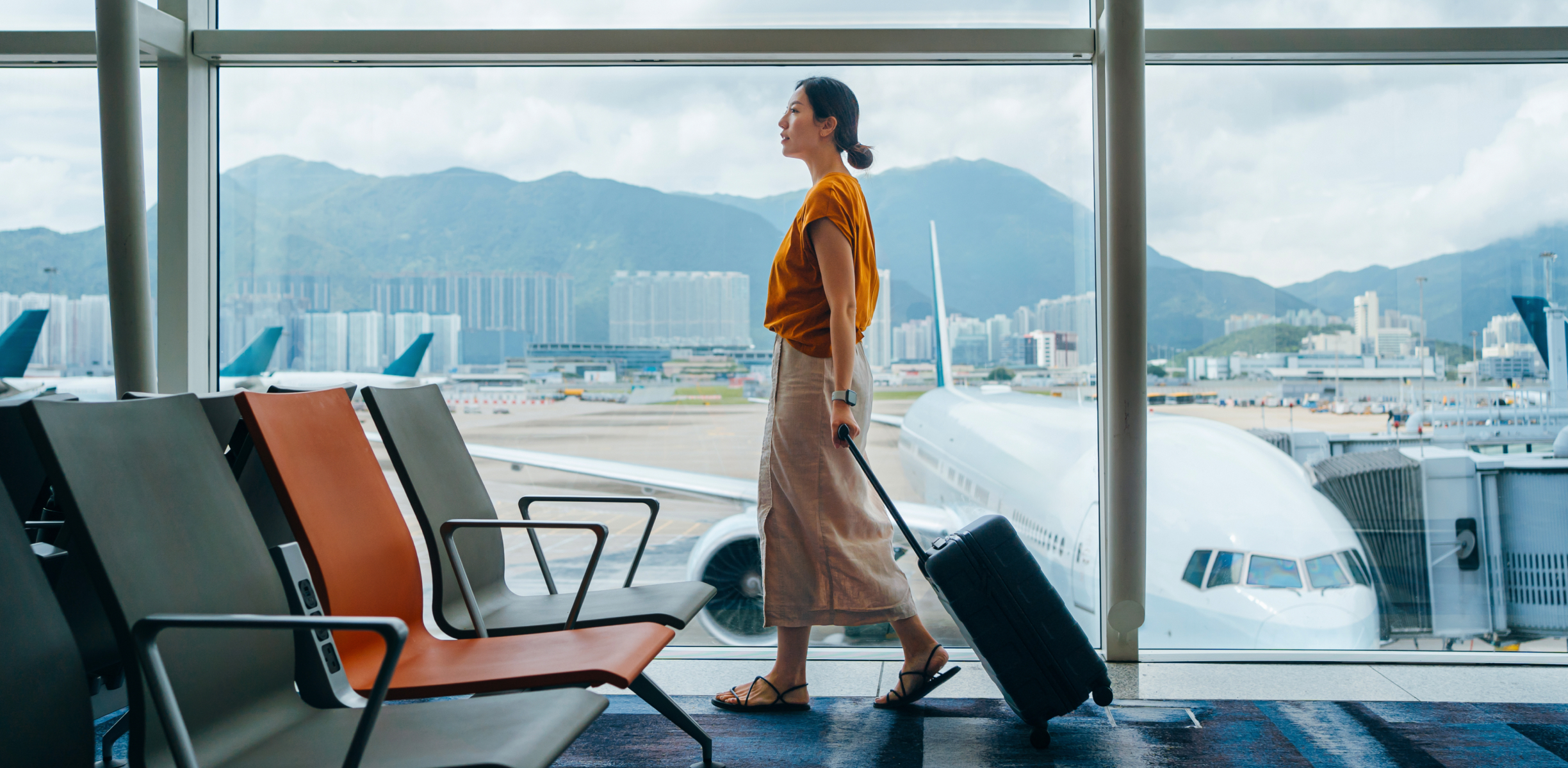 Frau zieht Rollkoffer durch das Terminal eines Flughafens