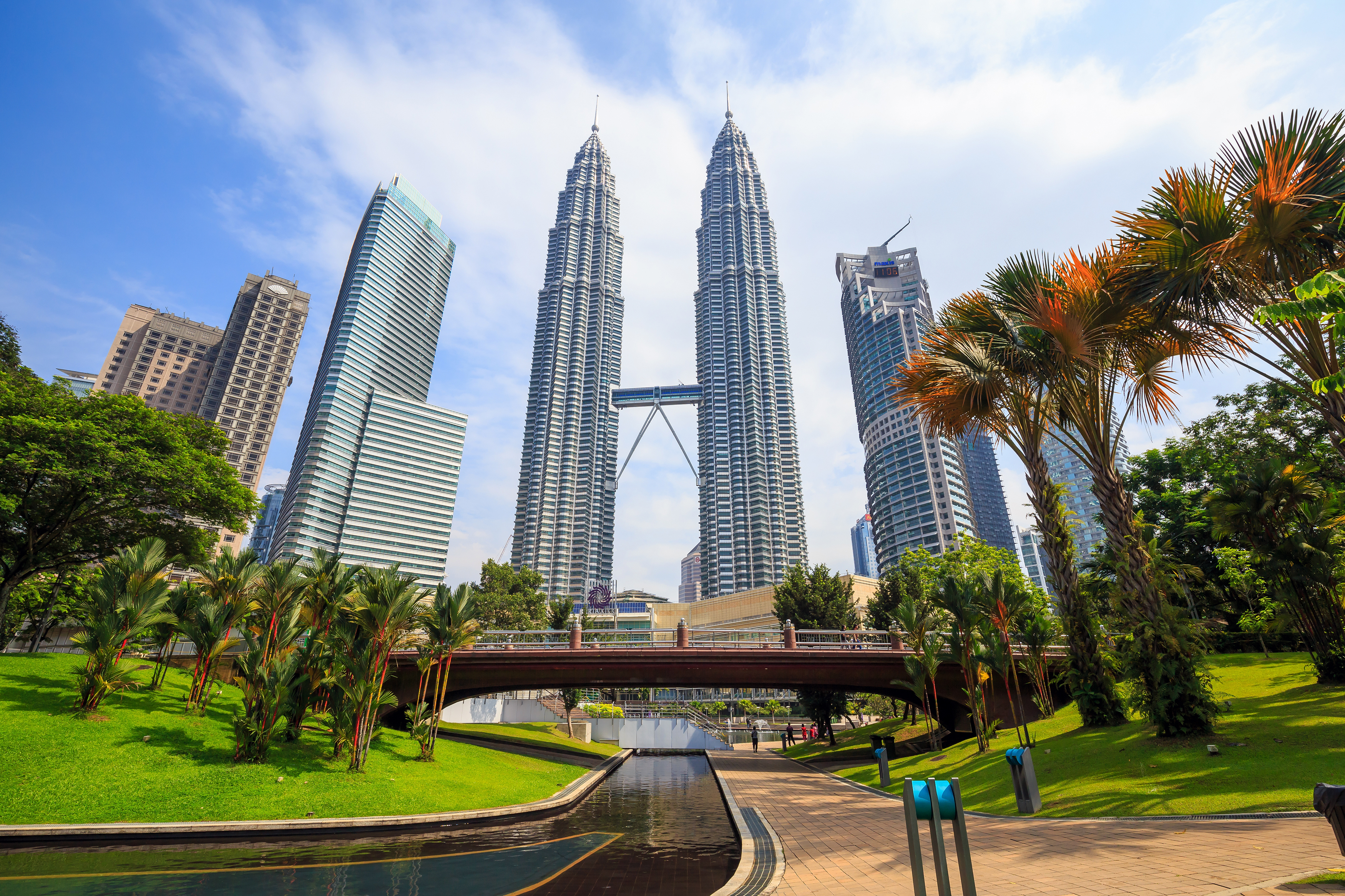 Petronas Twin Towers in Kuala Lumpur bei Sonnenuntergang mit moderner Skyline und beleuchteten Wolkenkratzern in Malaysia