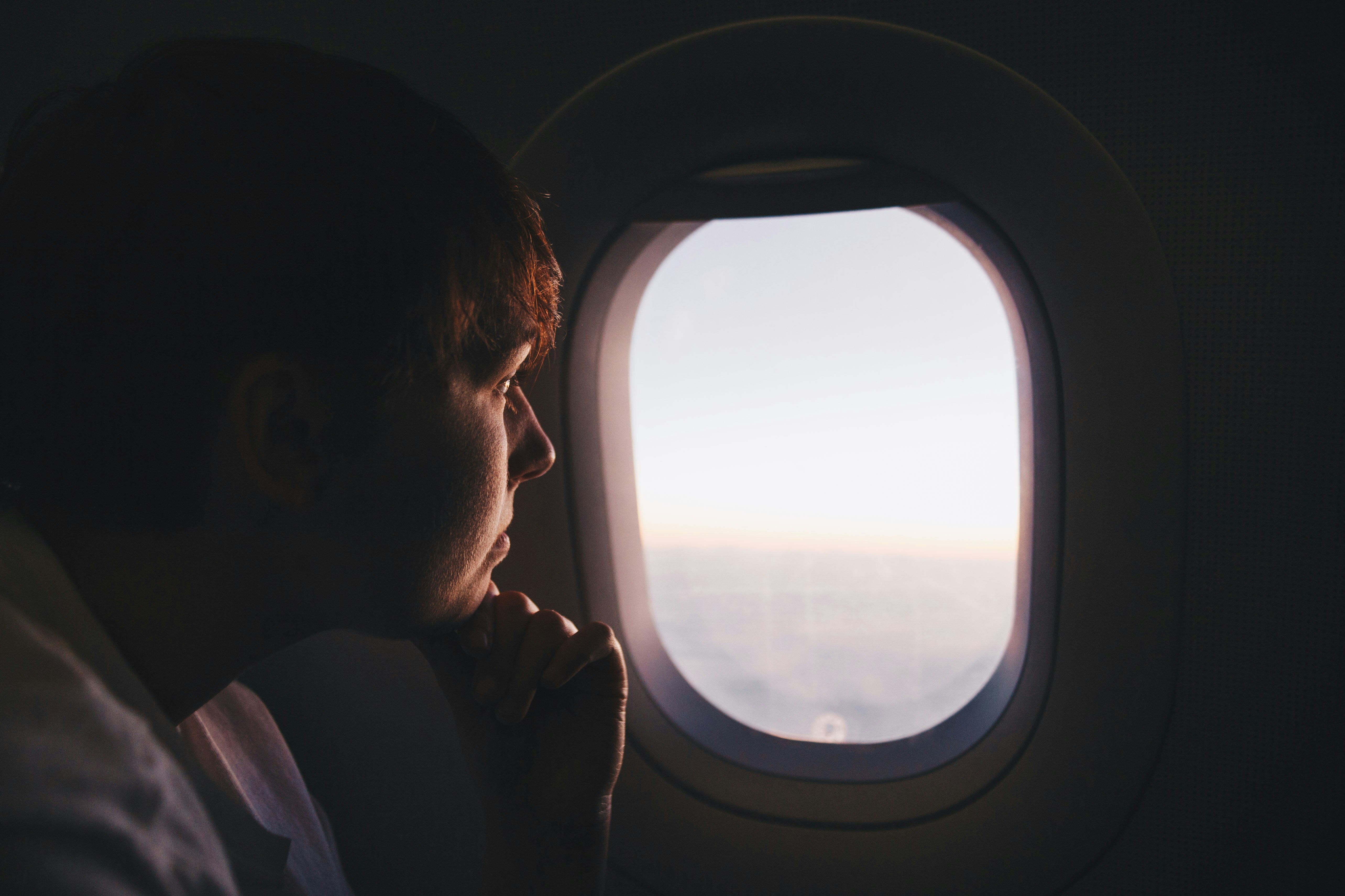 Reiziger kijkt uit het vliegtuigraam tijdens een vlucht
