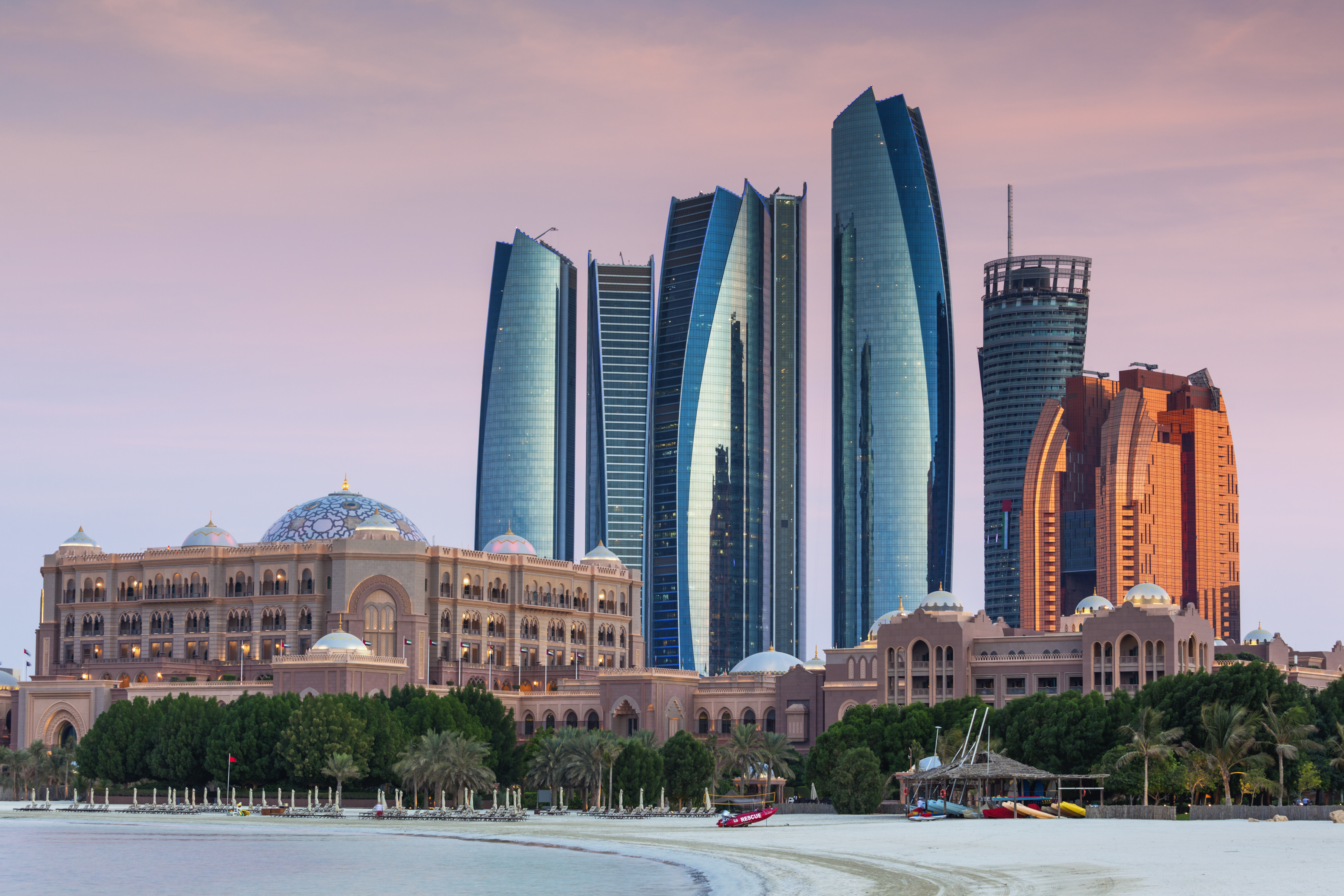 Panoramablick auf die moderne Skyline von Abu Dhabi mit markanten Wolkenkratzern entlang der Küste und dem türkisblauen Wasser des Arabischen Golfs.