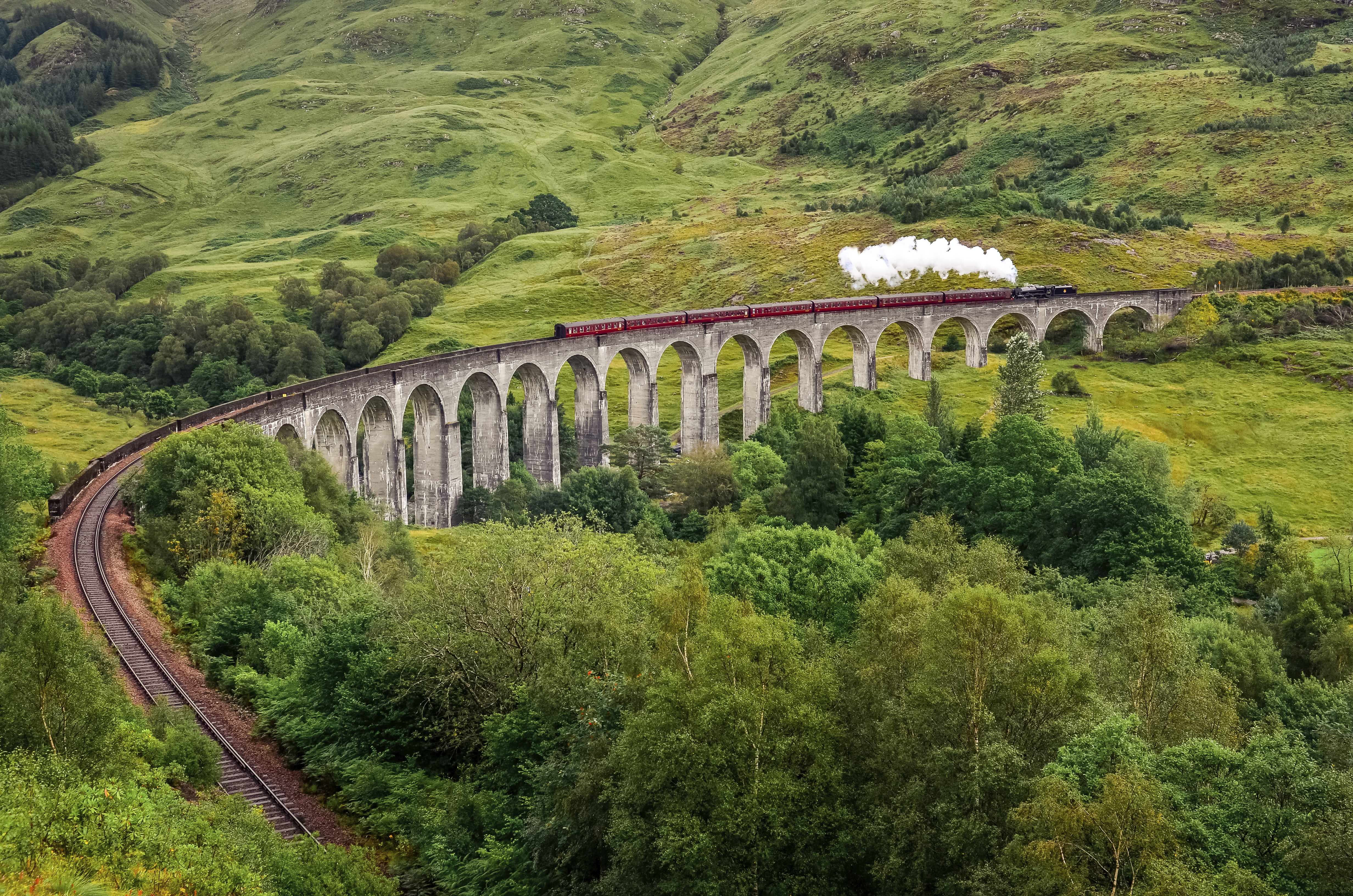 Trein van de West Highland Line rijdt over een iconische brug in de Schotse Highlands