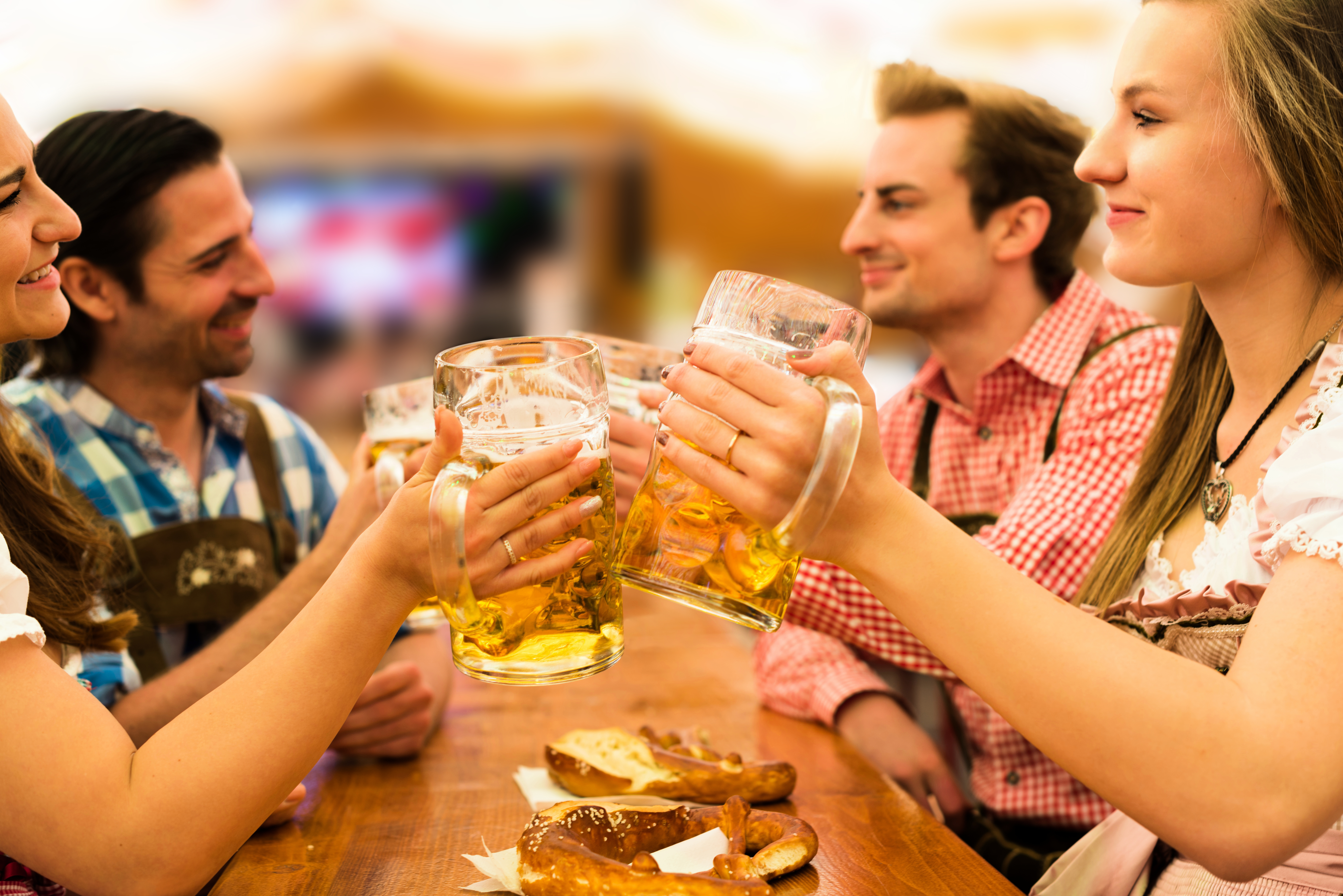 Personen in traditionele kleding zitten aan tafel met bierpullen tijdens het Oktoberfest