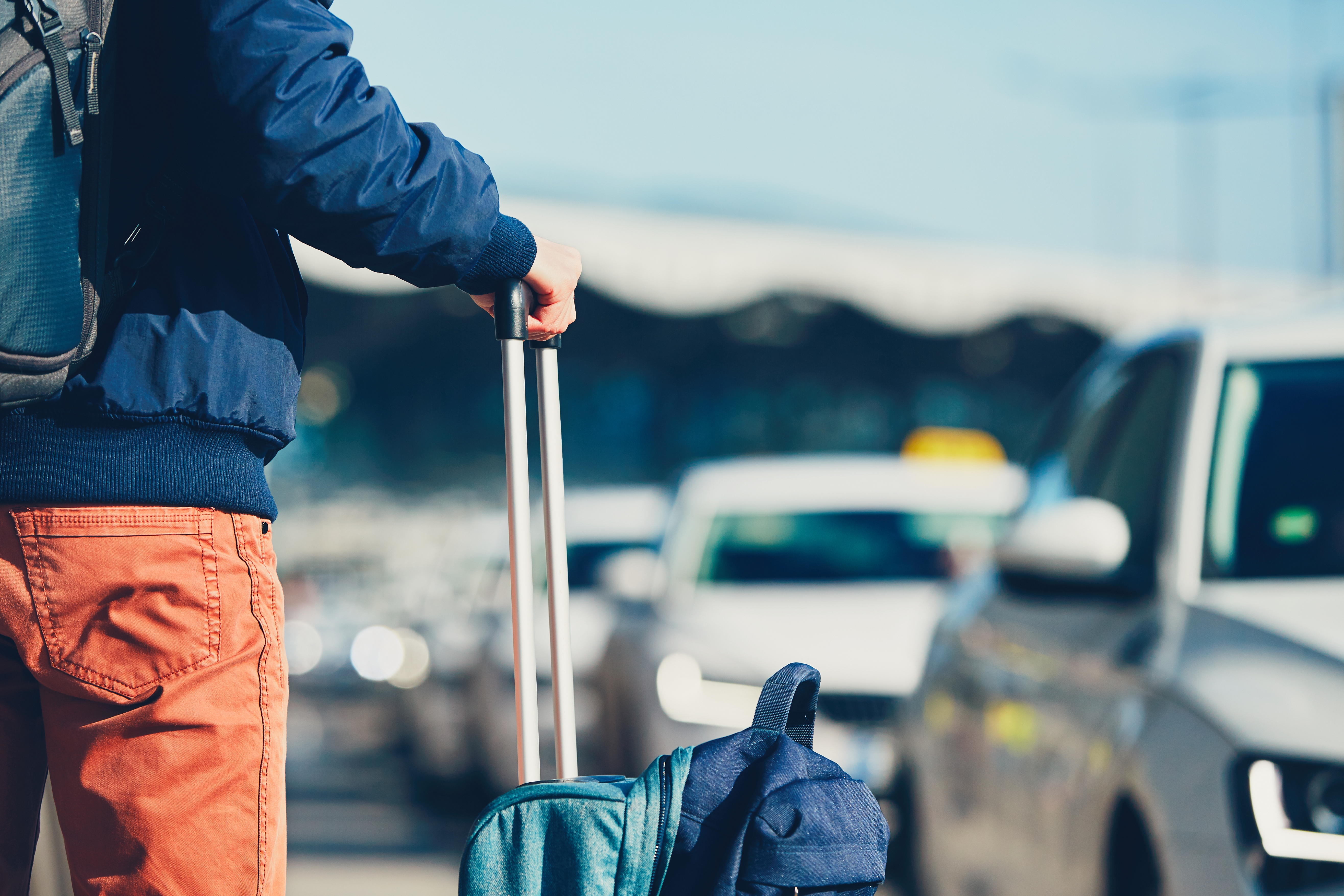 Reisender mit Handgepäck nach der Landung auf der Suche nach einem Taxi.