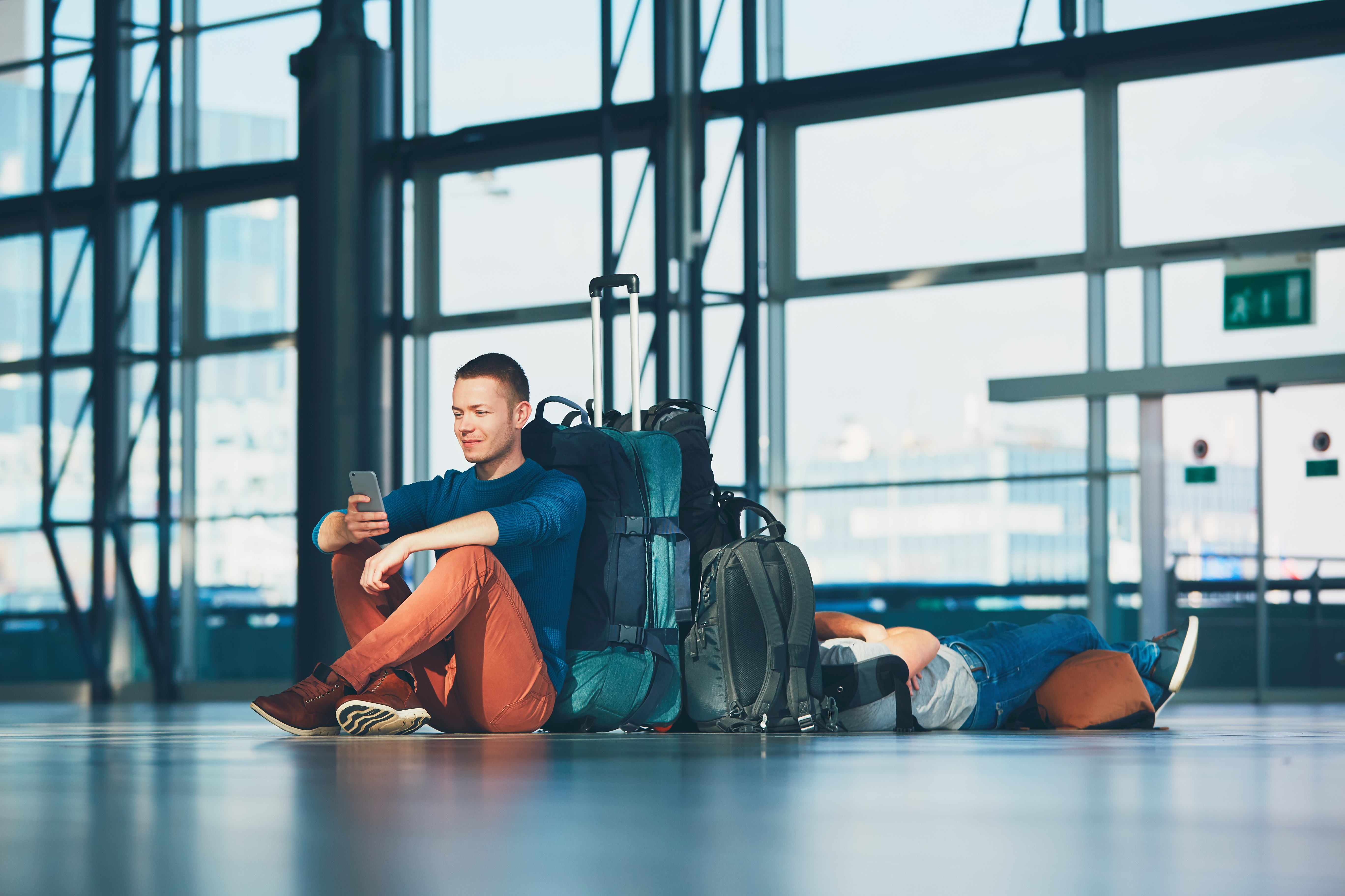 Reiziger met smartphone en koffers op een luchthaven