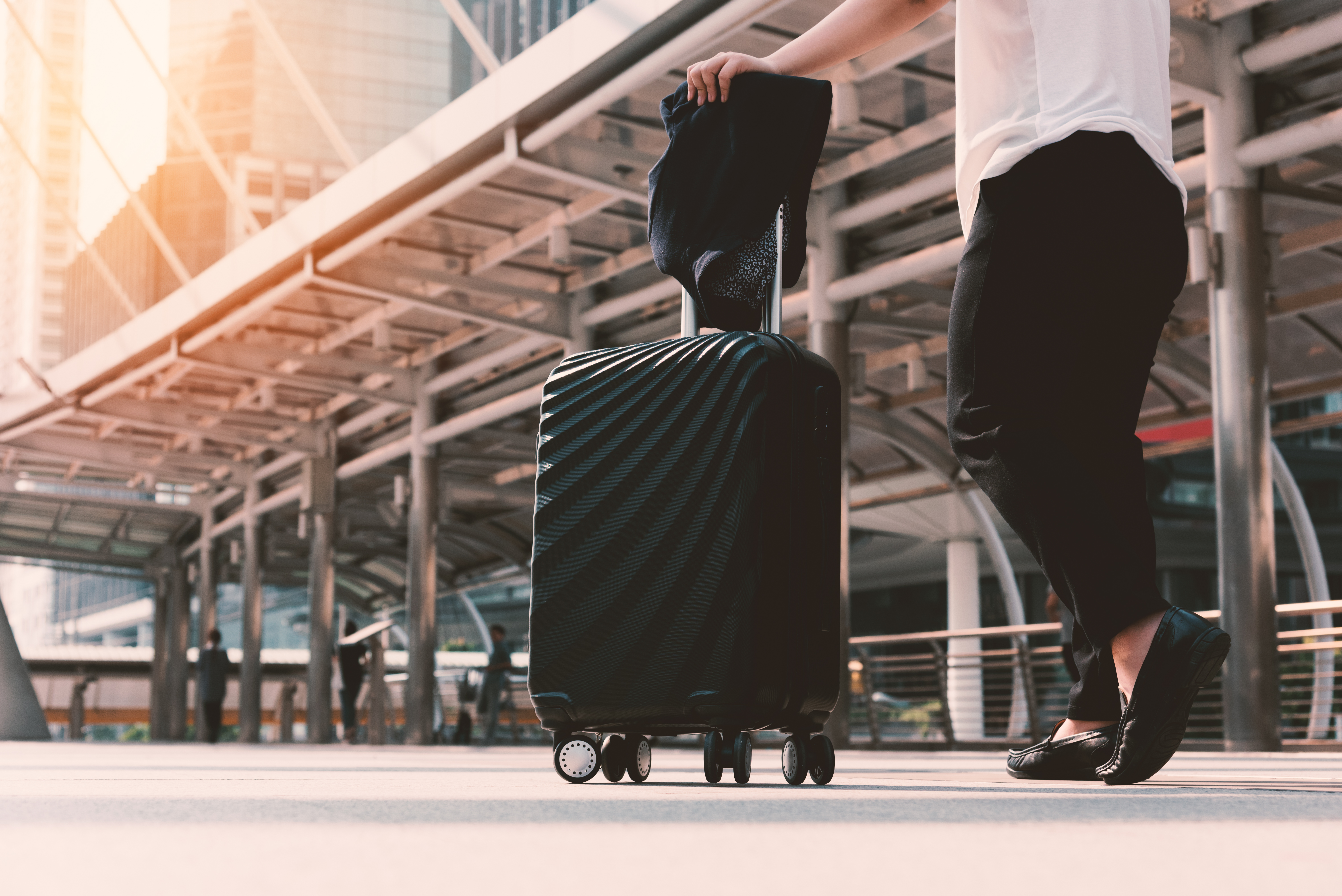 Passagier schiebt Rollkoffer durch die Abflughalle eines Flughafens