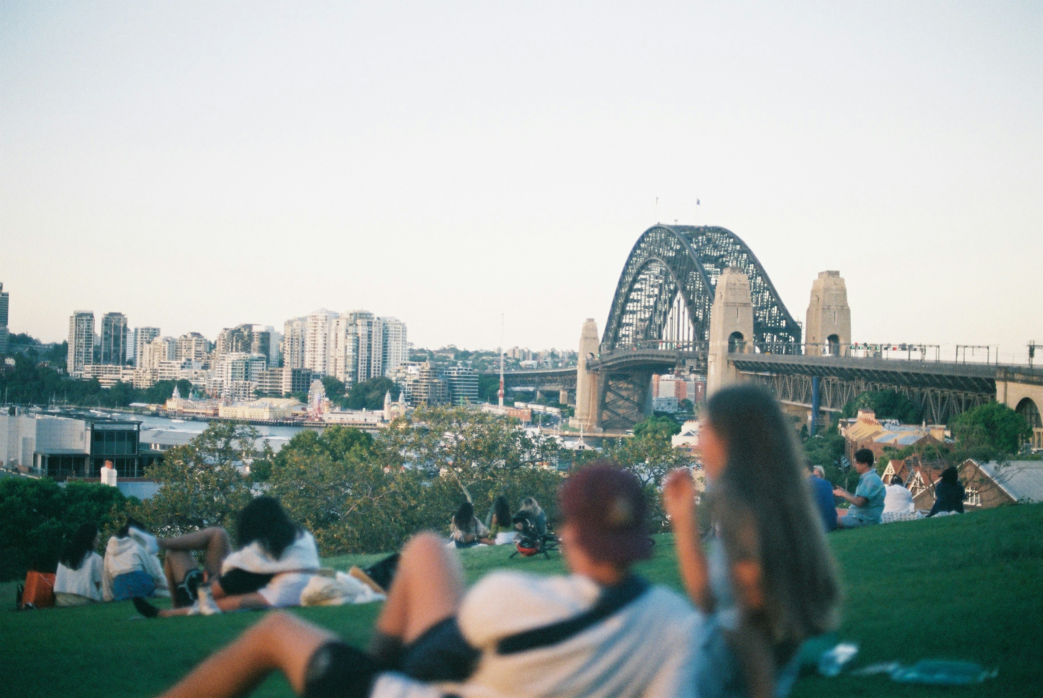Menschen auf einer Wiese mit Blick auf die Skyline von Sydney