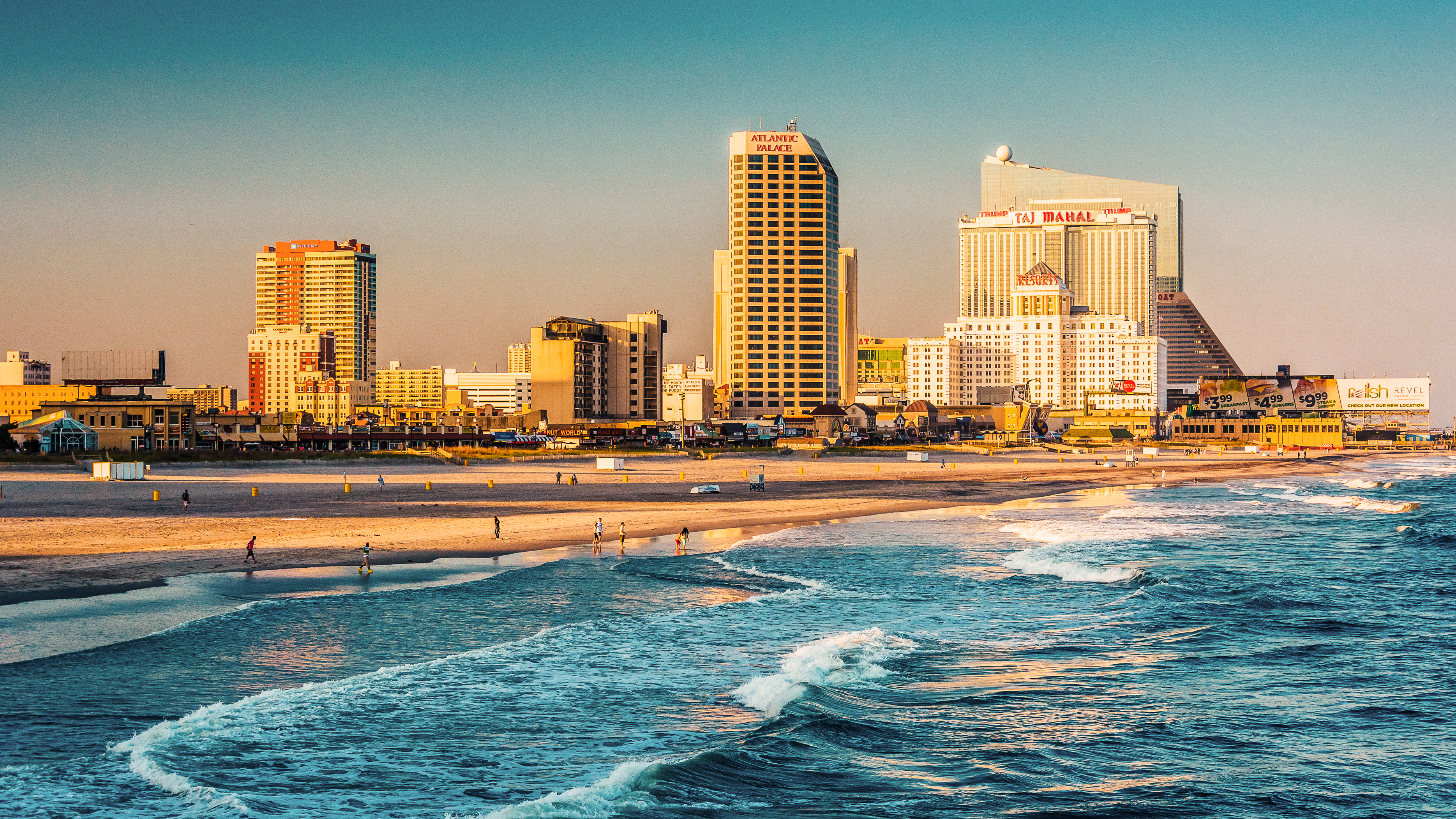 Atlantic city skyline in the background at dusk, with ocean waves and the beach in the foreground