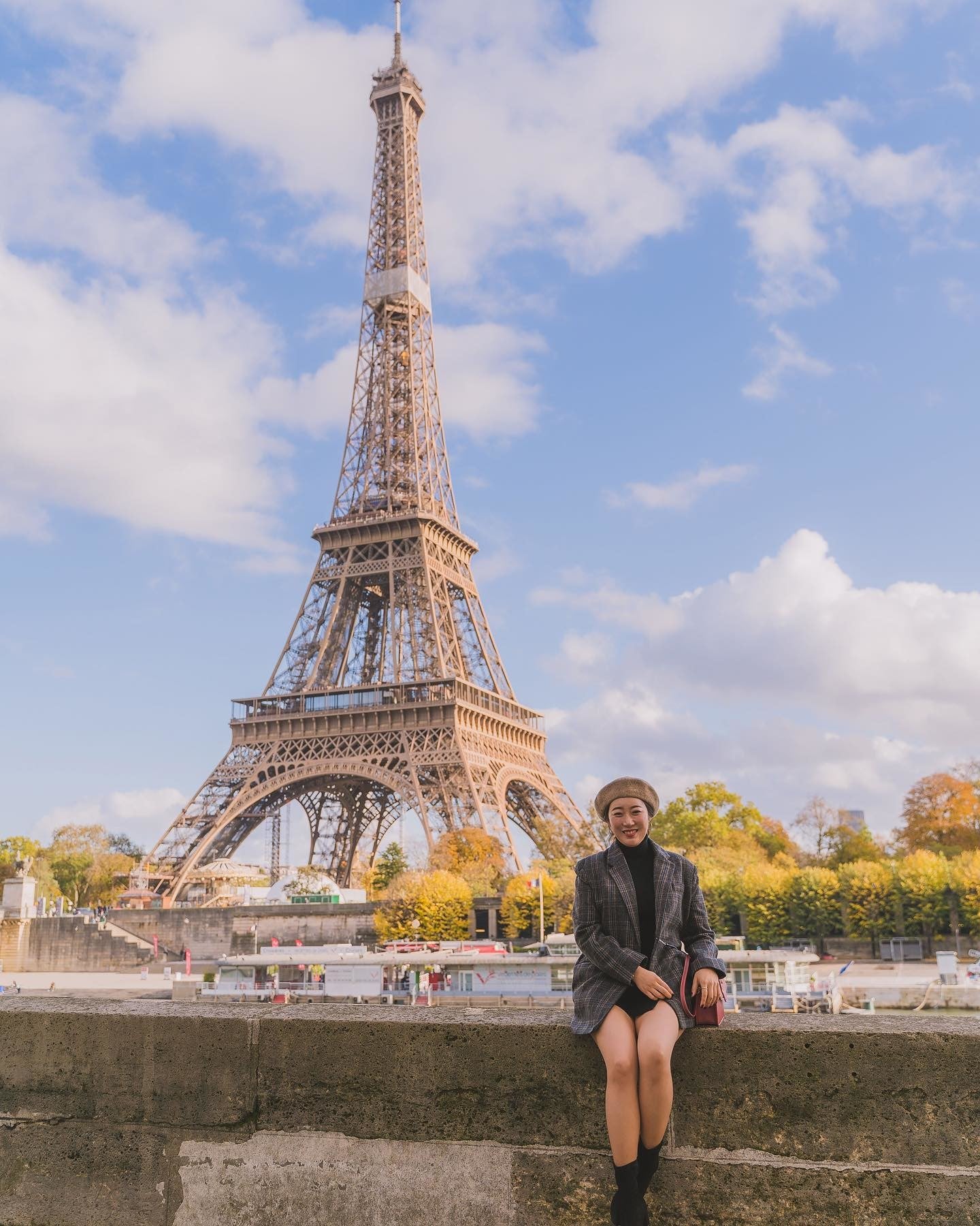 Woman sitting on stone wall with Eiffel Tower and the Seine in background