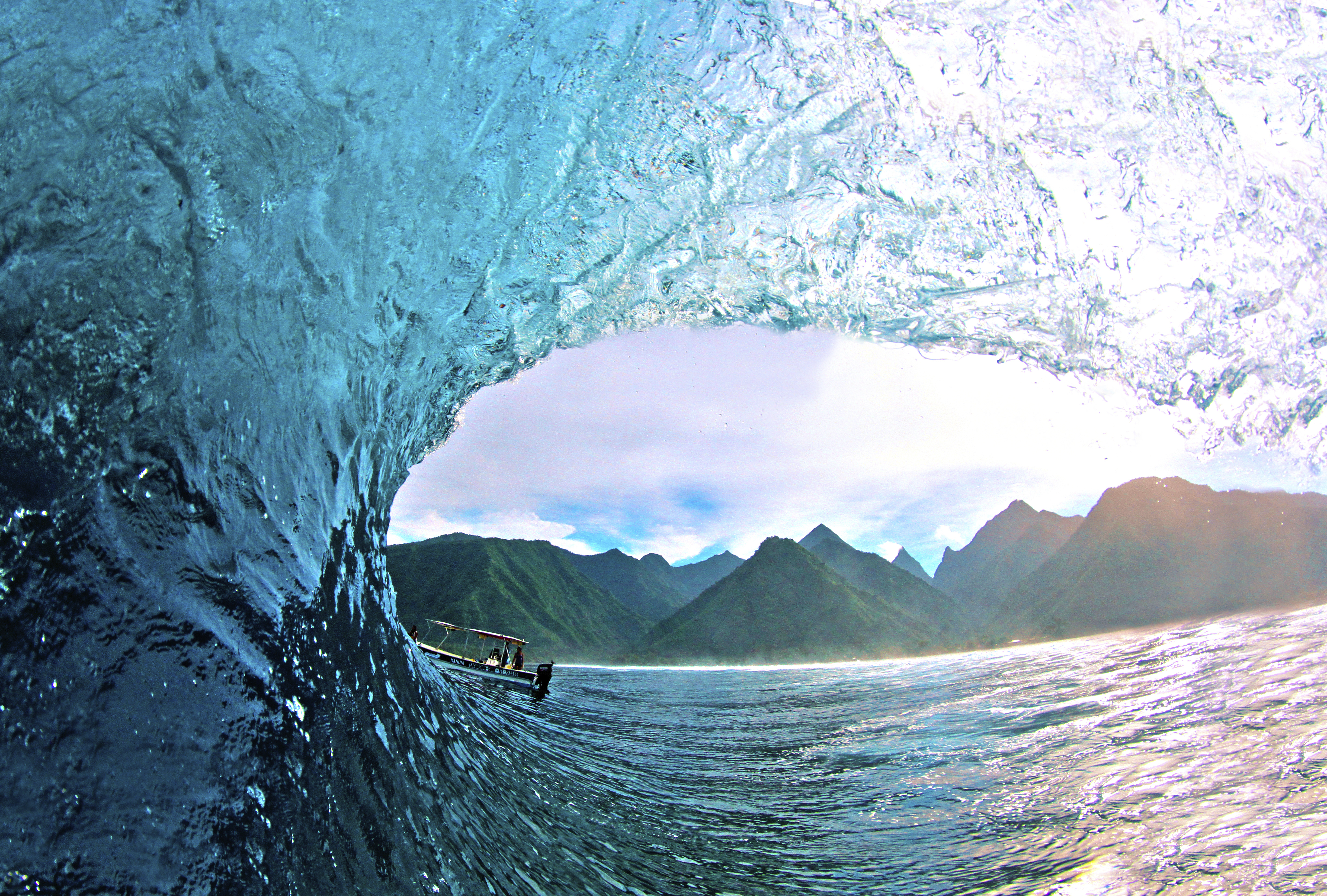 Barrel of a wave in Teahupo'o with green mountains in background