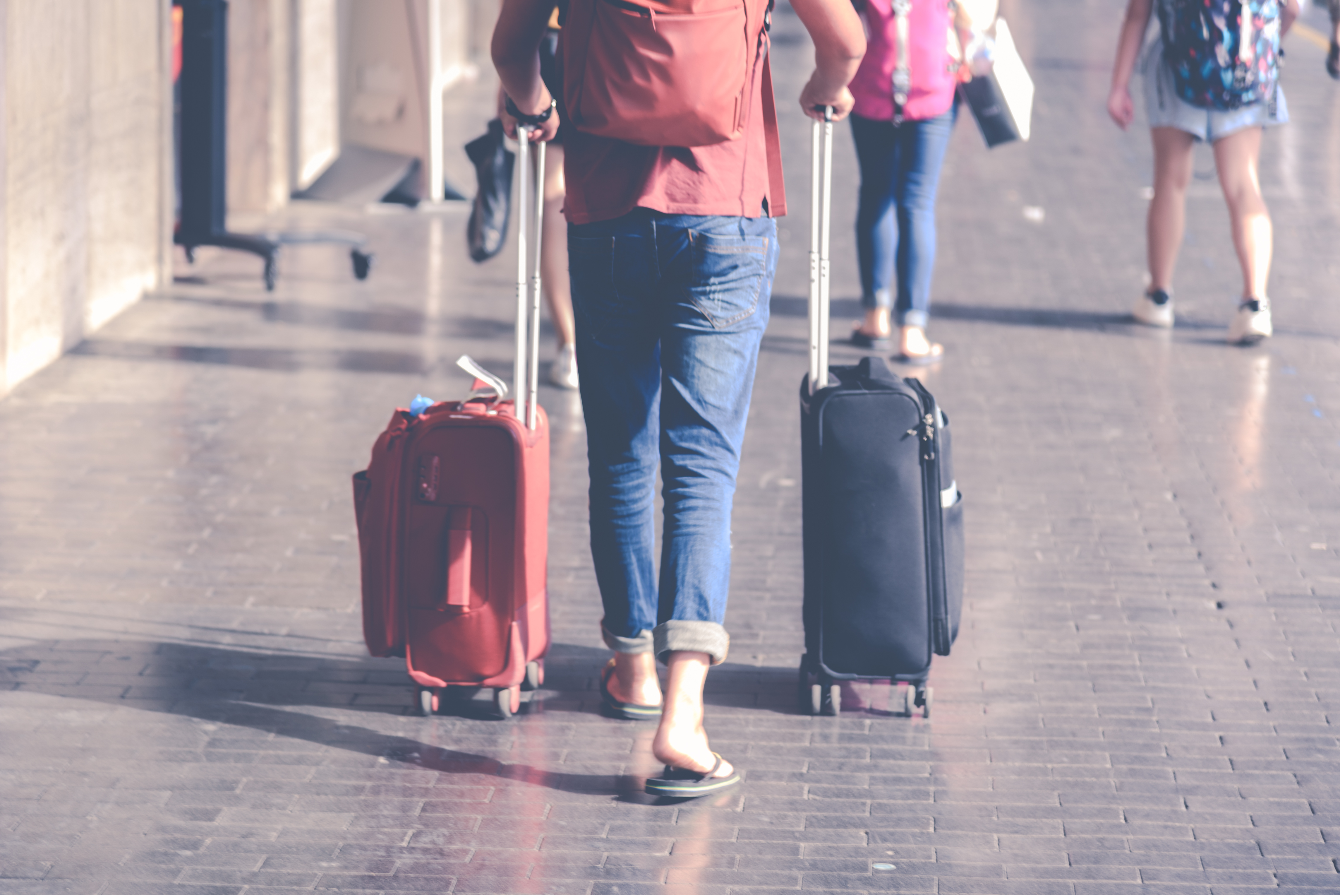 Reisende mit Rollkoffern im Terminal eines Flughafens vor dem Abflug