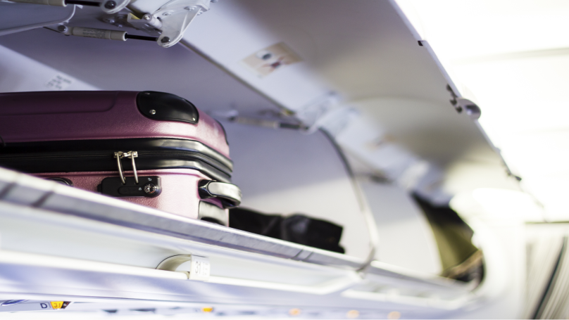 Handbagagekoffer in het bagagevak boven de stoelen in een vliegtuig